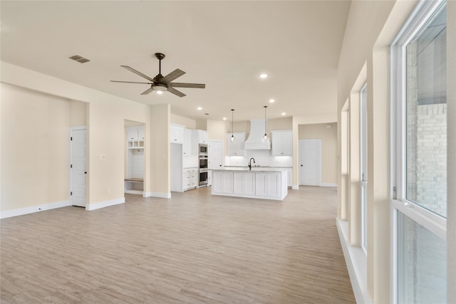 unfurnished living room featuring light hardwood / wood-style flooring, ceiling fan, and sink