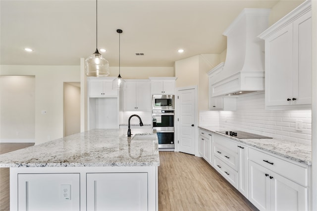 kitchen featuring premium range hood, white cabinets, a center island with sink, hanging light fixtures, and stainless steel appliances