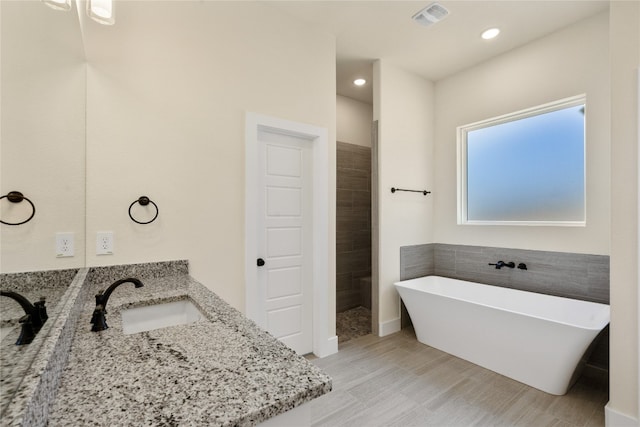 bathroom with hardwood / wood-style floors, vanity, and independent shower and bath