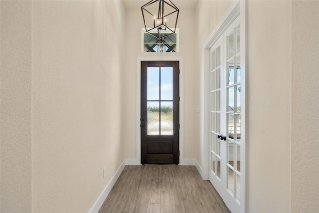 entryway featuring french doors, wood-type flooring, and an inviting chandelier