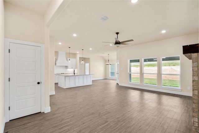 unfurnished living room with wood-type flooring and ceiling fan with notable chandelier