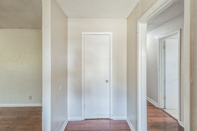 corridor featuring wood-type flooring and a textured ceiling