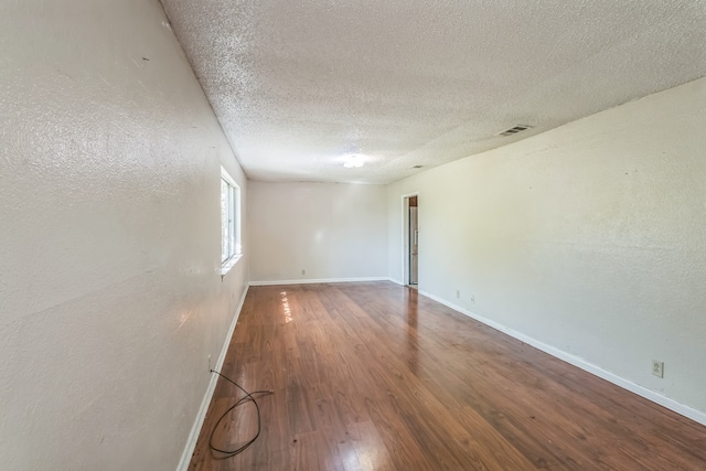 empty room with wood-type flooring and a textured ceiling