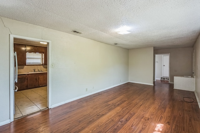 spare room featuring hardwood / wood-style flooring, sink, and a textured ceiling