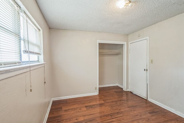 unfurnished bedroom with dark wood-type flooring, a closet, and a textured ceiling