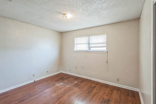 empty room featuring wood-type flooring and a textured ceiling