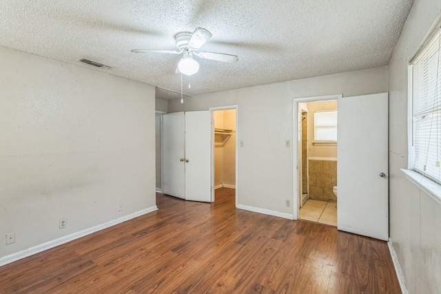 unfurnished bedroom featuring ceiling fan, hardwood / wood-style flooring, a textured ceiling, and a spacious closet