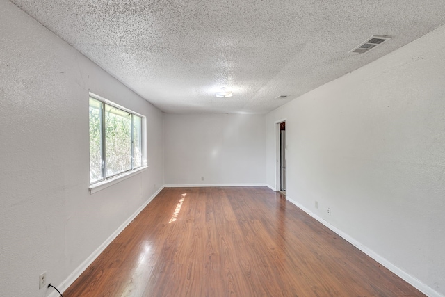 unfurnished room with dark wood-type flooring and a textured ceiling