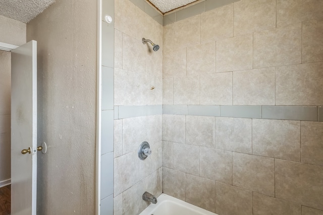 bathroom with tiled shower / bath and a textured ceiling