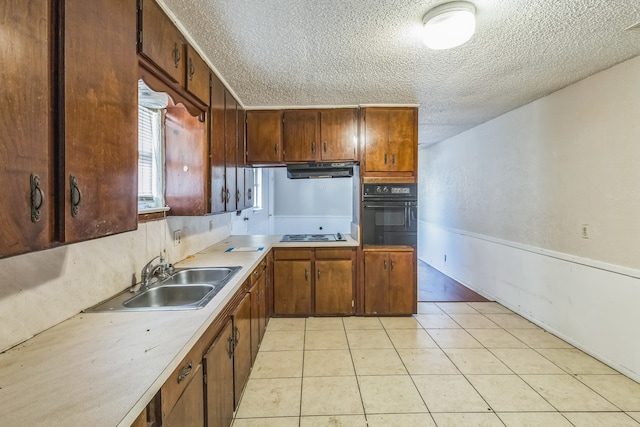 kitchen with light tile patterned floors, sink, oven, and a textured ceiling