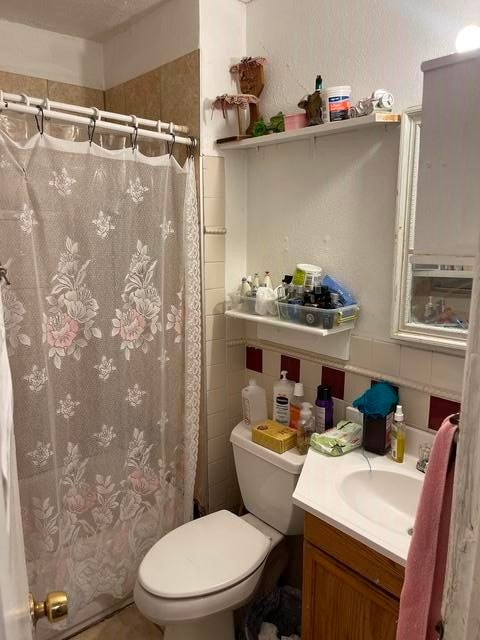 bathroom with toilet, vanity, and tile walls