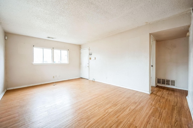 unfurnished room with a textured ceiling and light hardwood / wood-style floors