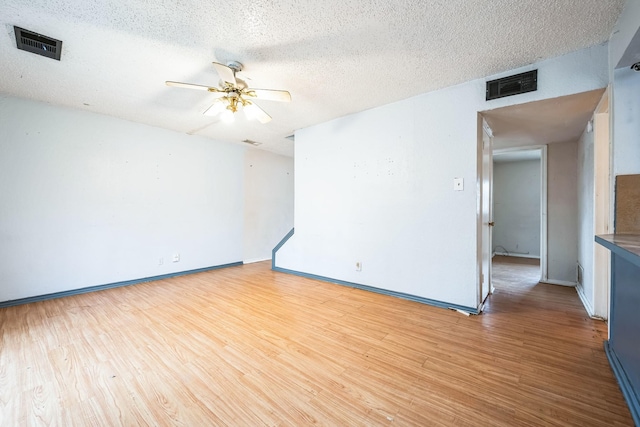 unfurnished room with ceiling fan, a textured ceiling, and light wood-type flooring