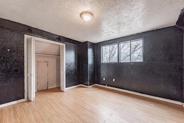 unfurnished bedroom featuring light hardwood / wood-style flooring, a textured ceiling, and a closet