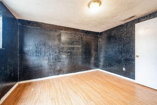 spare room featuring hardwood / wood-style flooring and a textured ceiling