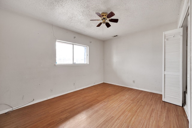 unfurnished bedroom with ceiling fan, a textured ceiling, and light wood-type flooring