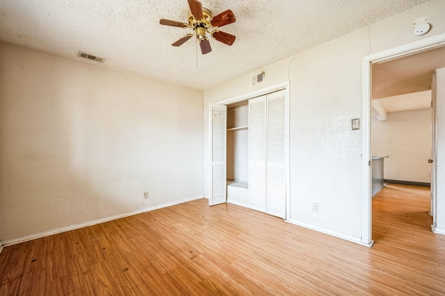 unfurnished bedroom with light wood-type flooring, a textured ceiling, ceiling fan, and a closet