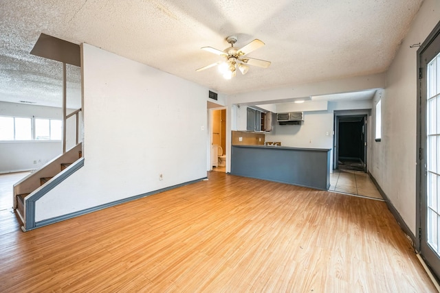 unfurnished living room with a textured ceiling, ceiling fan, and light hardwood / wood-style flooring