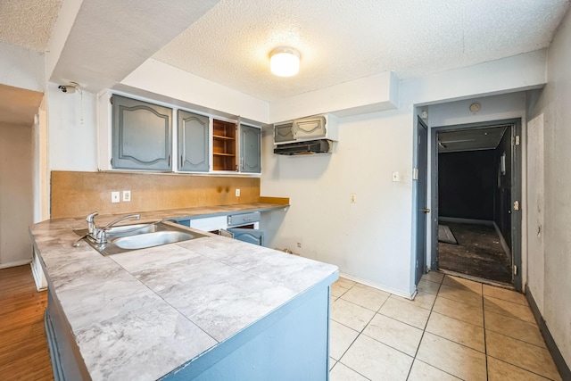 kitchen featuring tasteful backsplash, sink, a textured ceiling, and light tile patterned floors