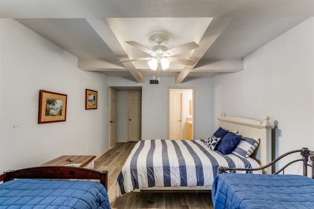 bedroom featuring ceiling fan, ensuite bath, dark hardwood / wood-style floors, and a tray ceiling