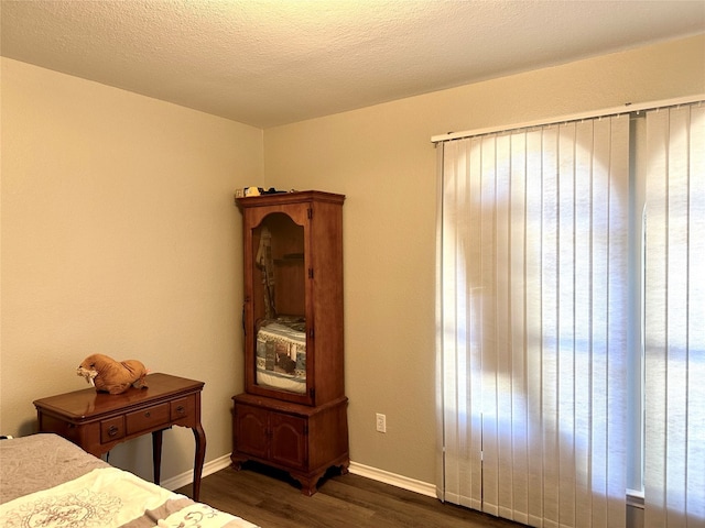 bedroom featuring a textured ceiling, multiple windows, and dark hardwood / wood-style floors