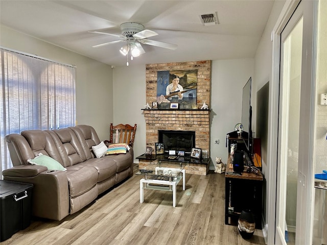 living room featuring a brick fireplace, ceiling fan, and light hardwood / wood-style flooring