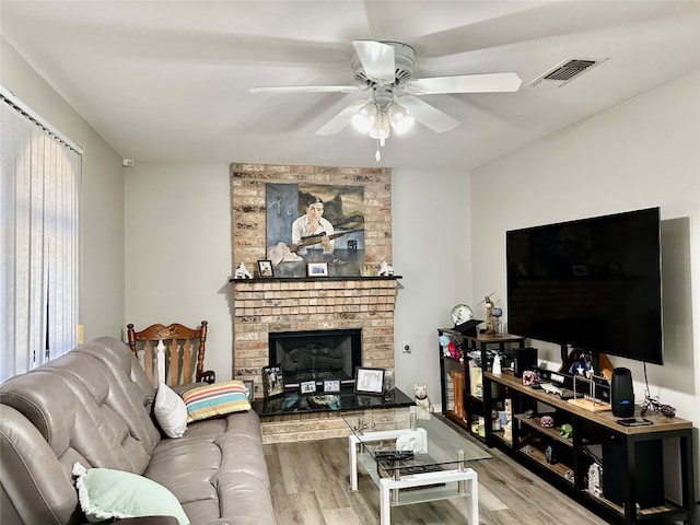 living room featuring a wealth of natural light, ceiling fan, light wood-type flooring, and a fireplace