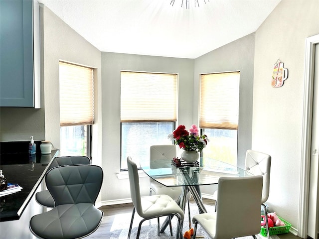 dining room with wood-type flooring and vaulted ceiling