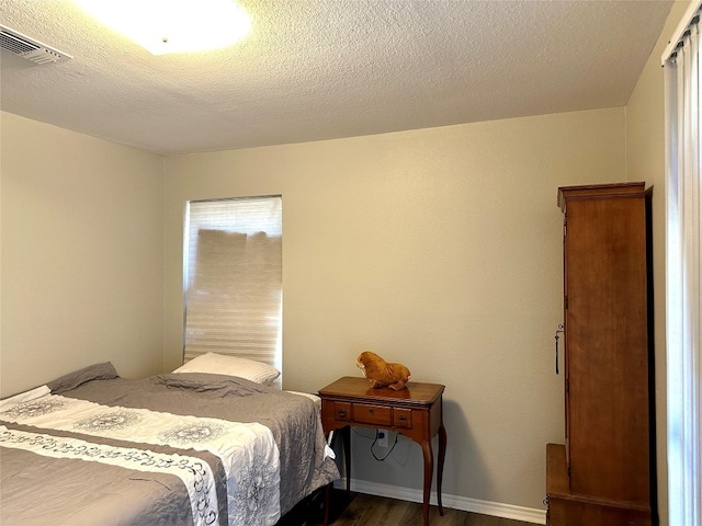 bedroom with a textured ceiling and dark hardwood / wood-style flooring