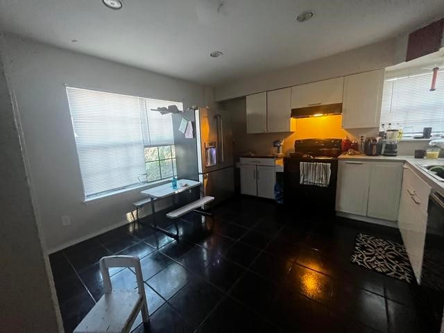 kitchen with dark tile floors, stainless steel fridge with ice dispenser, range, and white cabinetry