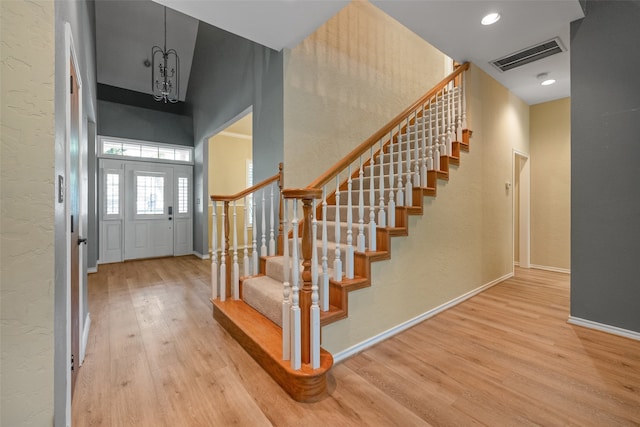 foyer featuring a towering ceiling, light hardwood / wood-style floors, and a notable chandelier