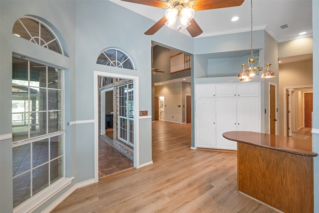 kitchen featuring ceiling fan with notable chandelier, pendant lighting, light hardwood / wood-style floors, and white cabinets