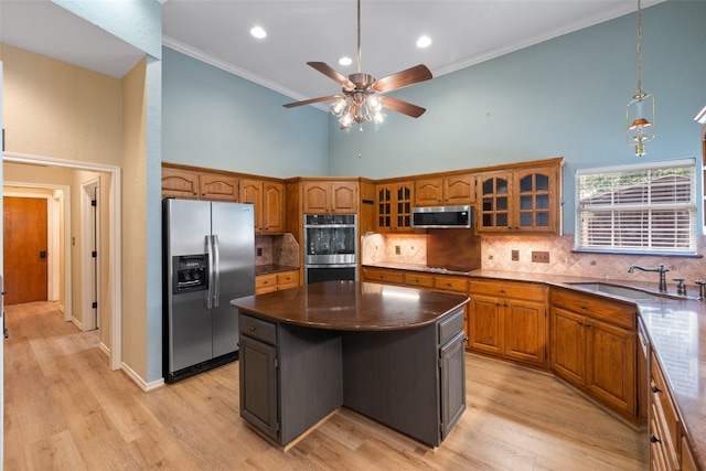 kitchen with appliances with stainless steel finishes, a kitchen island, high vaulted ceiling, backsplash, and light hardwood / wood-style flooring