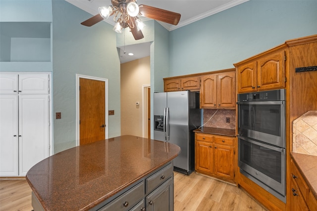 kitchen with backsplash, light hardwood / wood-style floors, stainless steel appliances, and ceiling fan