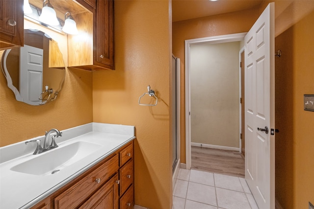 bathroom with tile flooring, vanity, and a shower with shower door