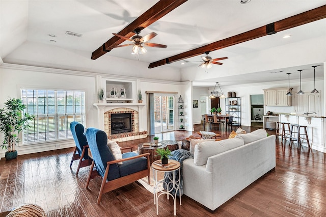 living room with ceiling fan, dark wood-type flooring, beamed ceiling, and a fireplace