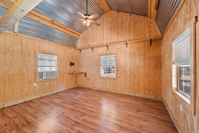 empty room with light hardwood / wood-style floors, wooden walls, ceiling fan, lofted ceiling with beams, and wood ceiling