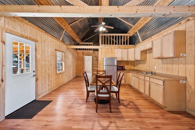 interior space with vaulted ceiling with beams, ceiling fan, sink, light hardwood / wood-style flooring, and wood walls