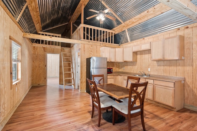 dining space featuring wooden walls, light hardwood / wood-style floors, ceiling fan, and sink