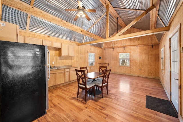 interior space featuring ceiling fan, light brown cabinets, light hardwood / wood-style flooring, and black refrigerator