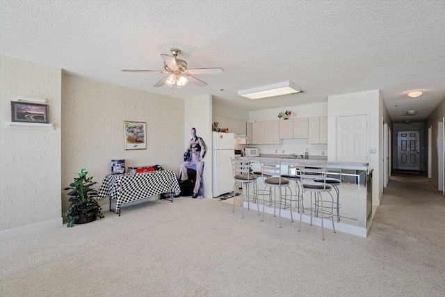 kitchen featuring a kitchen bar, light carpet, white fridge, and ceiling fan