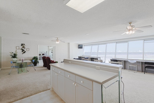 kitchen with ceiling fan, a water view, light tile floors, and a textured ceiling