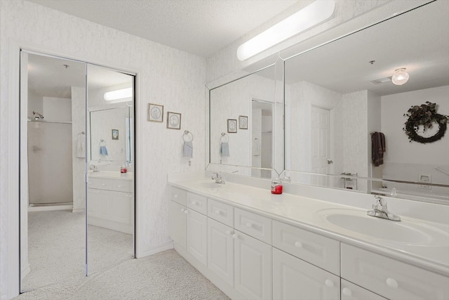 bathroom with double sink, a shower with door, and vanity with extensive cabinet space