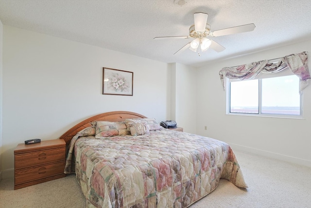 bedroom featuring a textured ceiling, ceiling fan, and light colored carpet