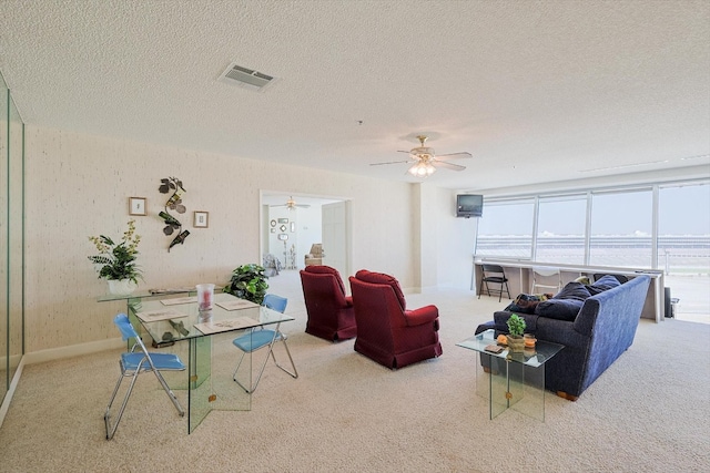 living room featuring ceiling fan, a water view, light colored carpet, and a textured ceiling