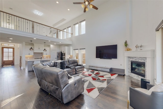 living room with dark hardwood / wood-style flooring, ceiling fan, and a high ceiling