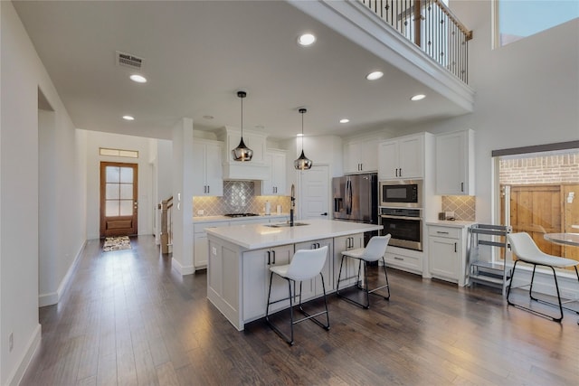 kitchen featuring appliances with stainless steel finishes, dark wood-type flooring, white cabinetry, and decorative light fixtures