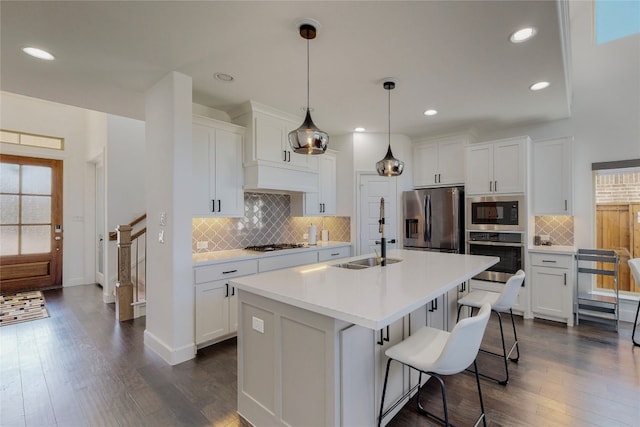 kitchen with tasteful backsplash, stainless steel appliances, white cabinets, and hanging light fixtures