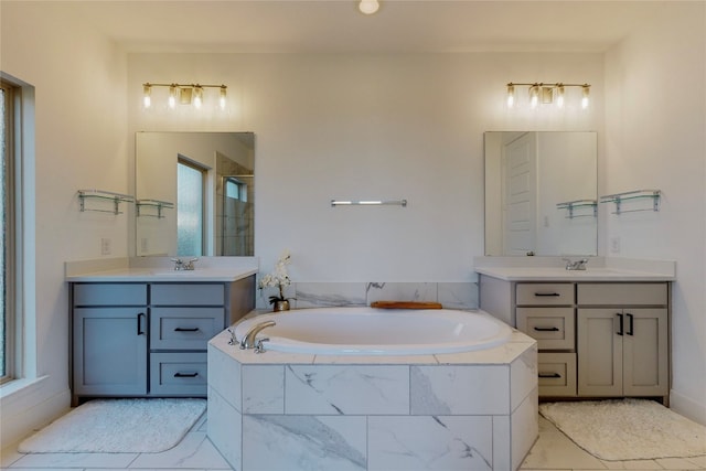 bathroom featuring tiled tub, dual vanity, and tile flooring