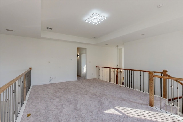 spare room featuring light carpet and a tray ceiling